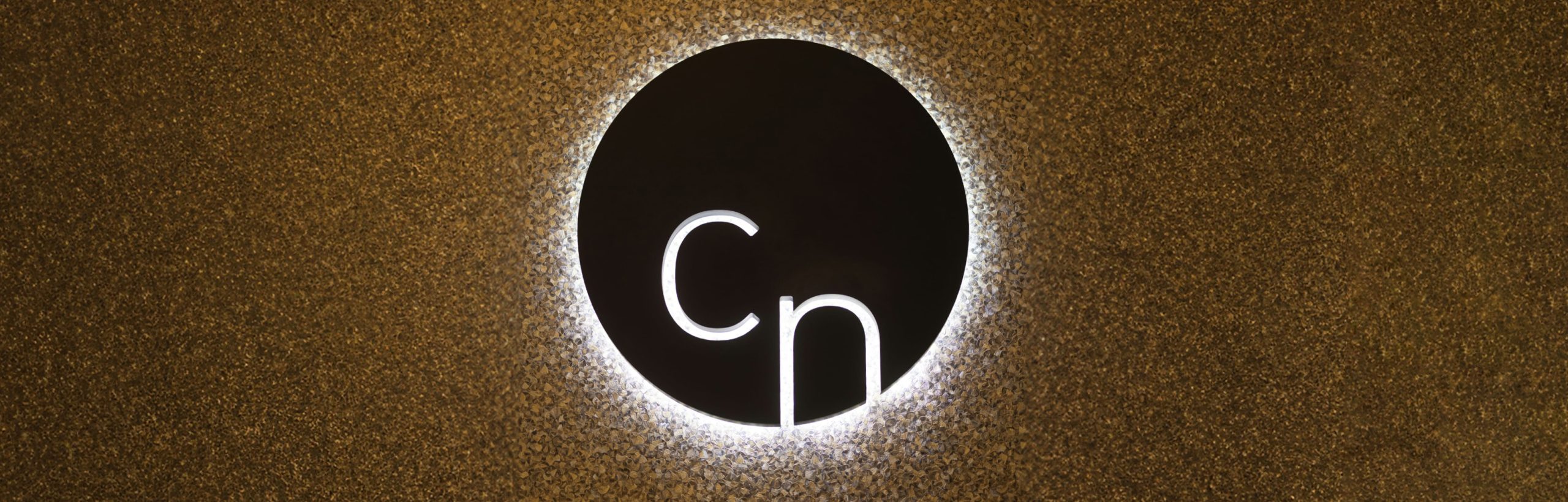 Beleuchtetes Cn-Logo an der goldenen Wand im Kosmetikinstitut