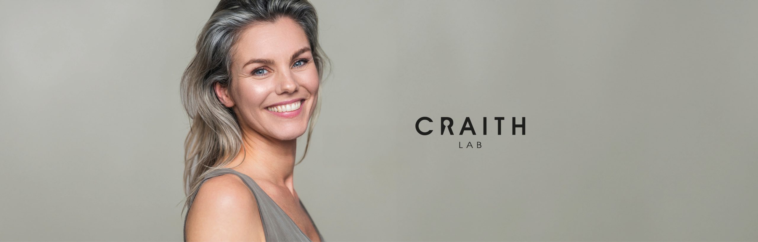 Lächelnde Frau mit grauen Haaren neben dem Craith Lab Logo