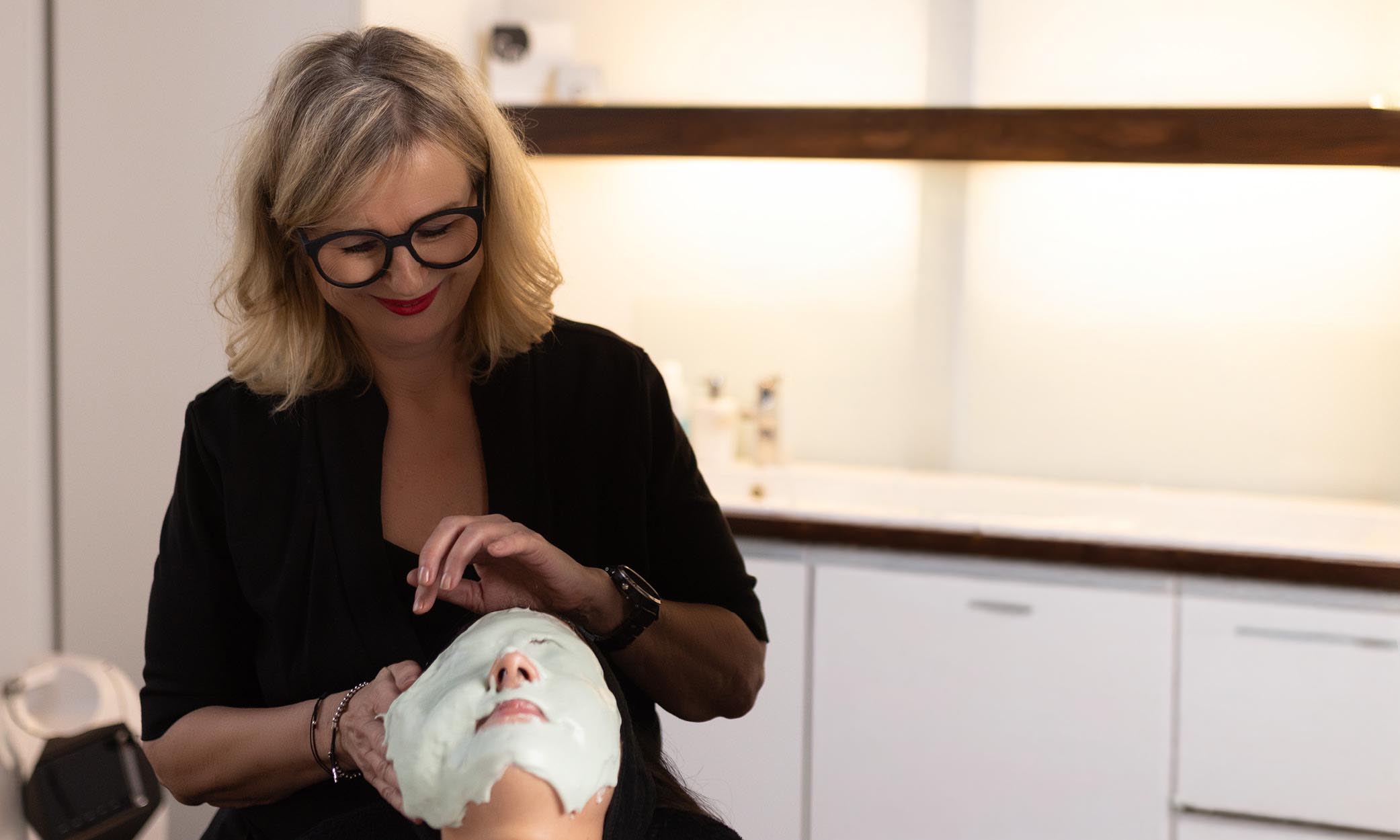 Christiane Niemand trägt einer Kundin eine Modelliermaske im Behandlungsraum auf